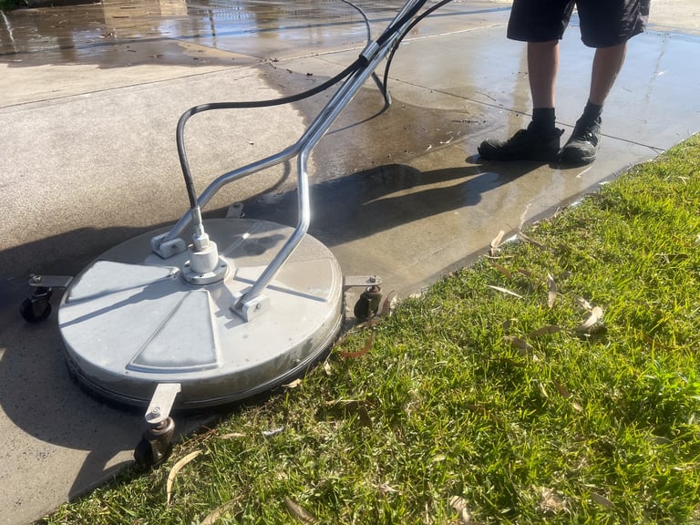 Worker using a pressure washer to clean surfaces with high-pressure water spray.